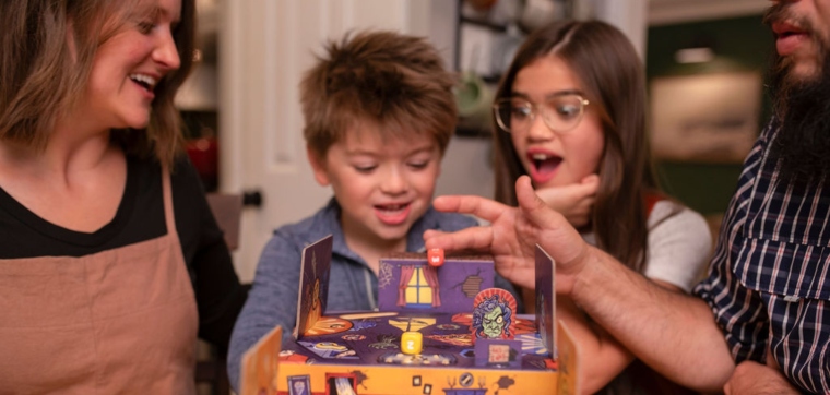 A family with little children playing the board game Boxtop Pinball Haunted Hause from Pandasaurus.