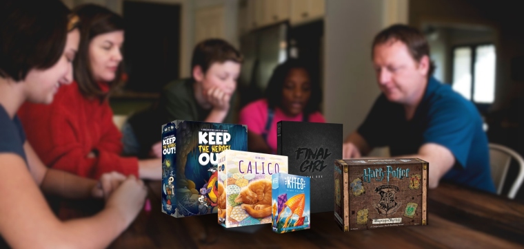 In the background people are playing a game and are laughing. In the front the board games and card games Keep The Heroes Out!, Calico, Kites, Final Girl Core Box, and Harry Potter Hogwarts Battle.