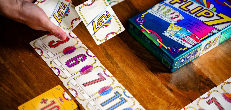 Someone playing the party game and card game Flip 7 from The Op (USAopoly).