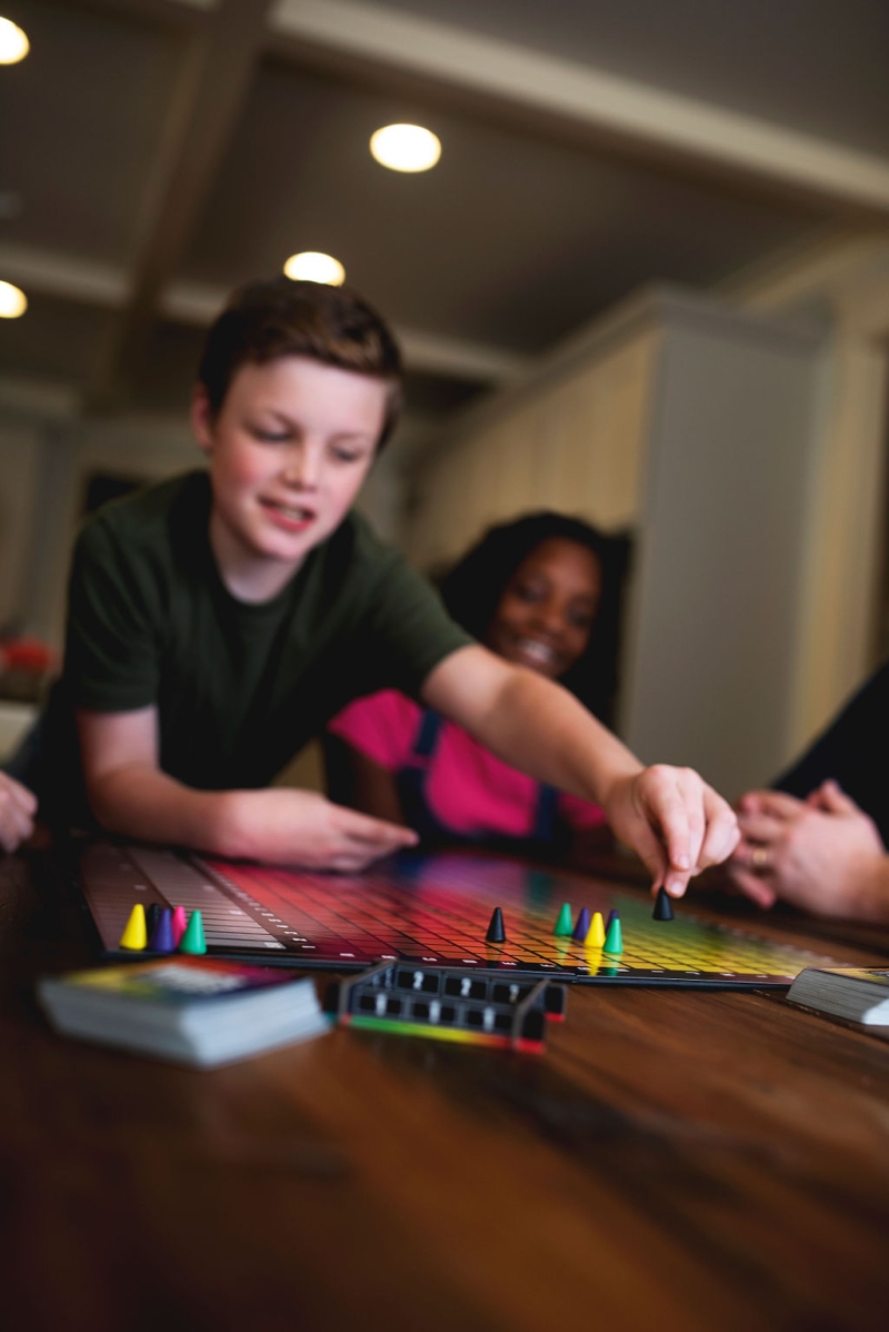 A lifestyle photo of a family playing the partygame Hues and Cues.